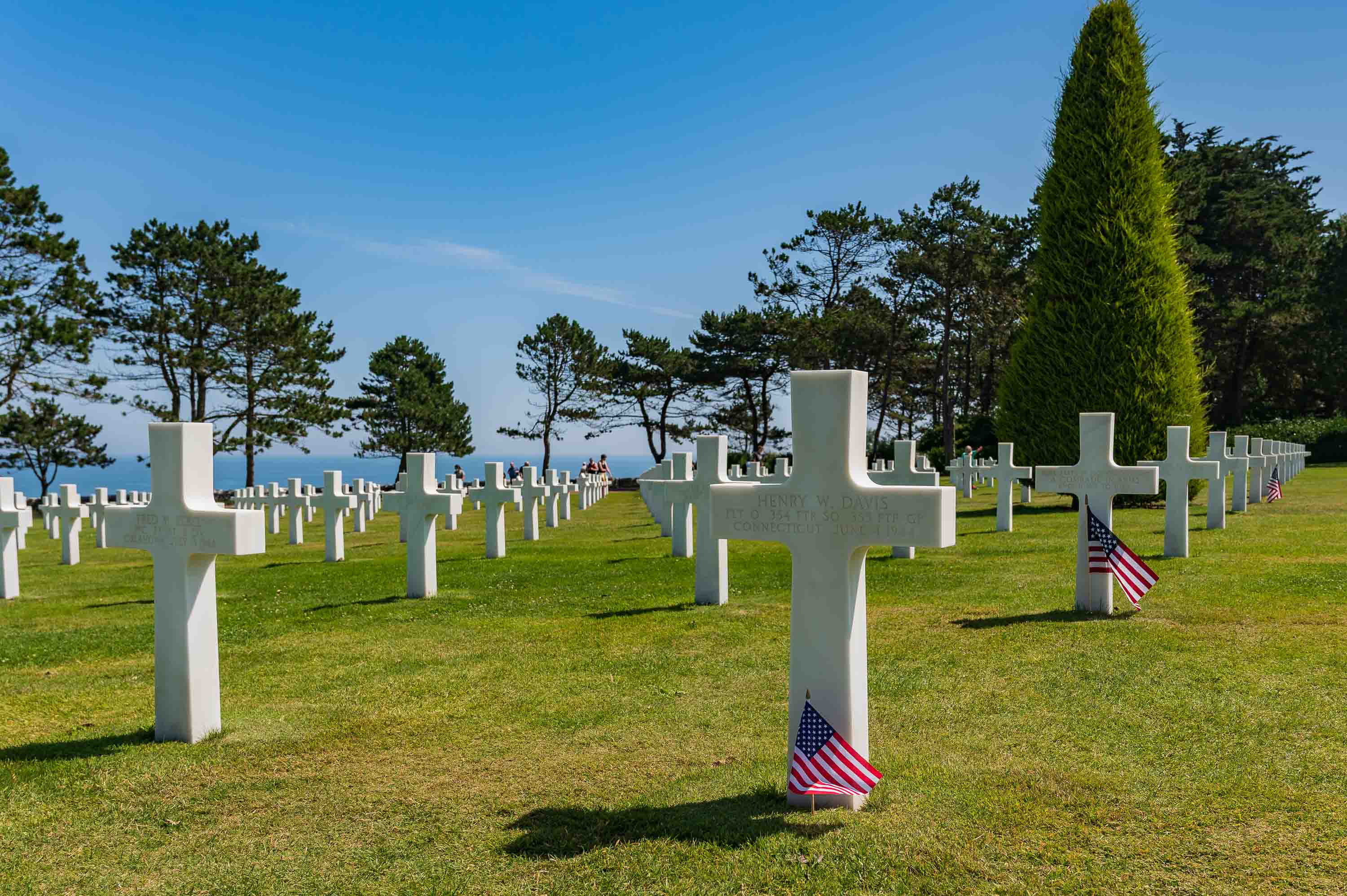 Cruces blancas y banderas americanas en el Cementerio Americano de Colleville-sur-Mer, frente al mar.