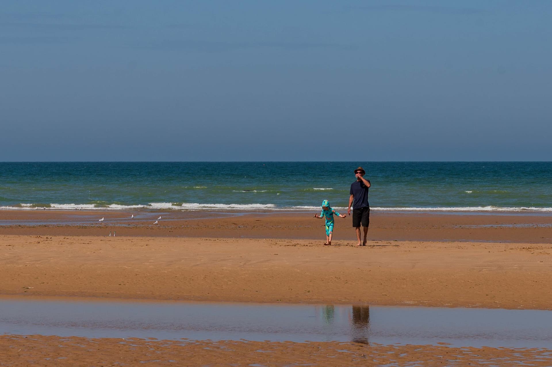 Un padre y su hija caminan hoy por una playa que hace 80 años fue un campo de batalla.