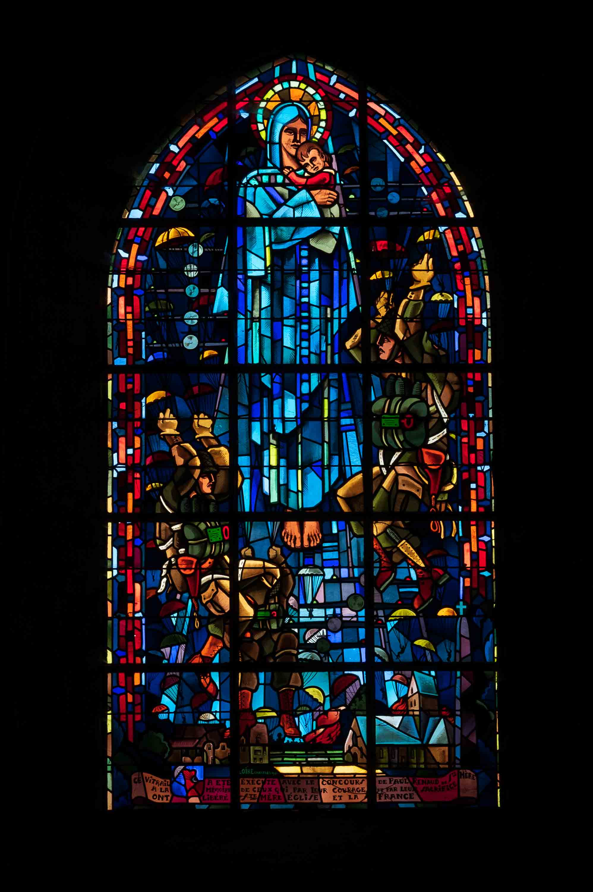 Vitral en la iglesia de Sainte-Mère-Église, con la Virgen rodeada de paracaidistas.