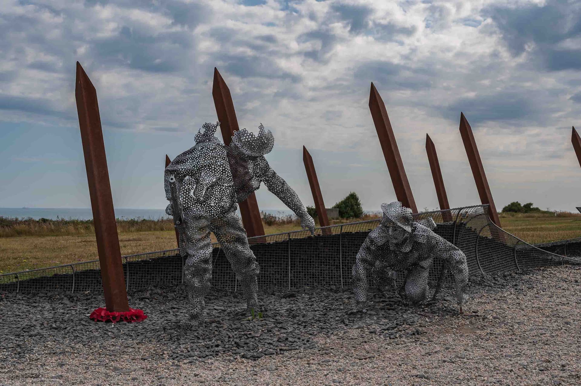 Coronas de amapolas rojas depositadas junto a las figuras del memorial, en homenaje a los caídos.