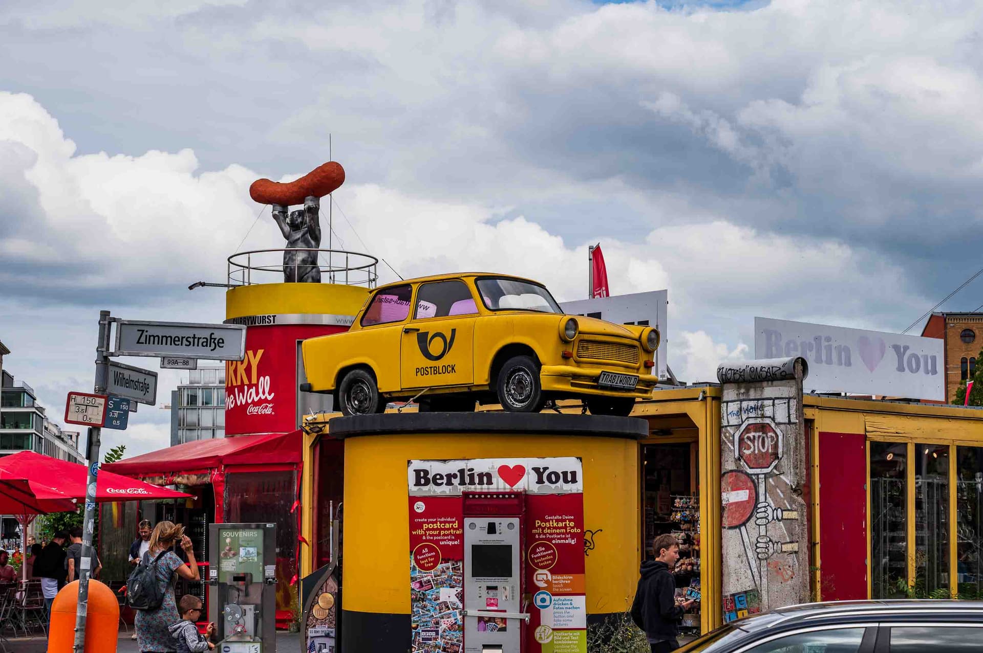 The Checkpoint Charlie kiosk: a yellow Trabant, a giant sausage, and "Berlin ❤ You" in technicolor.