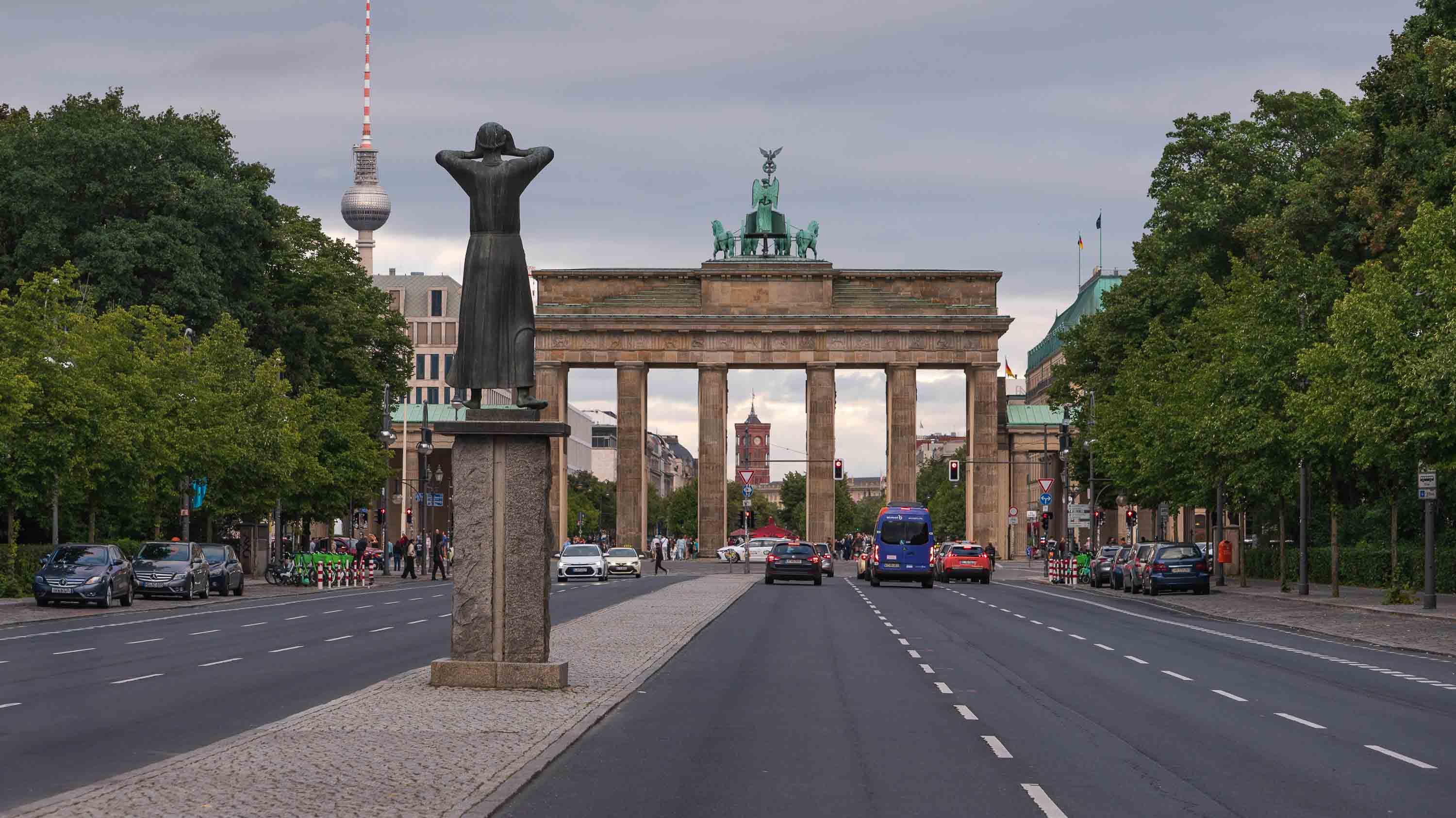 Die Rufer, seen from behind, contemplates the Brandenburg Gate from Unter den Linden. To the left, the Fernsehturm.