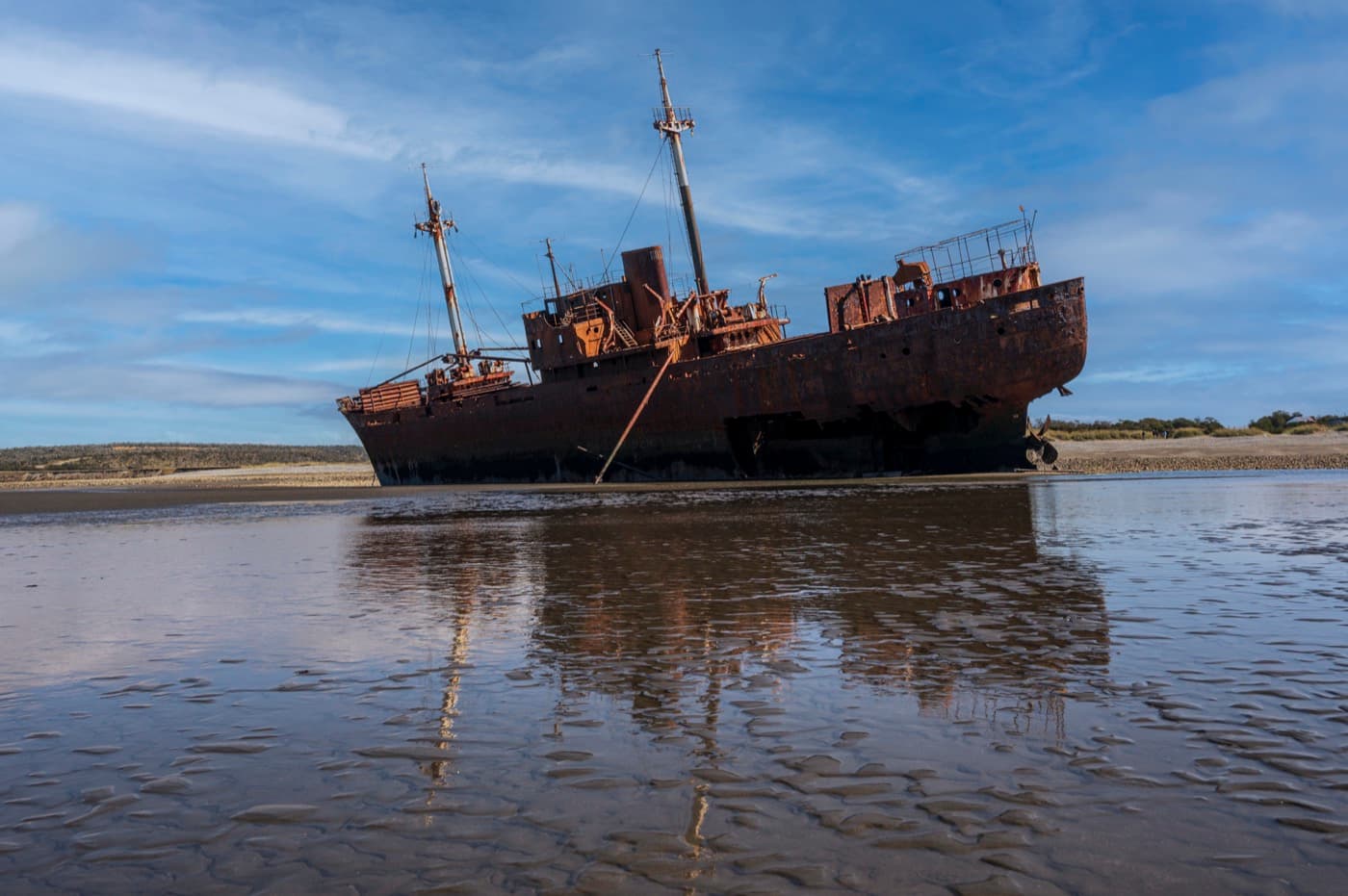 The Desdémona reflected in the water left by the low tide on the beach at Cabo San Pablo